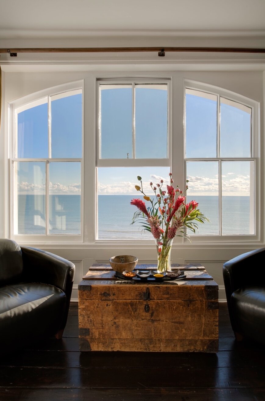 Africa Room — arched seafront window with flowers and leather armchairs