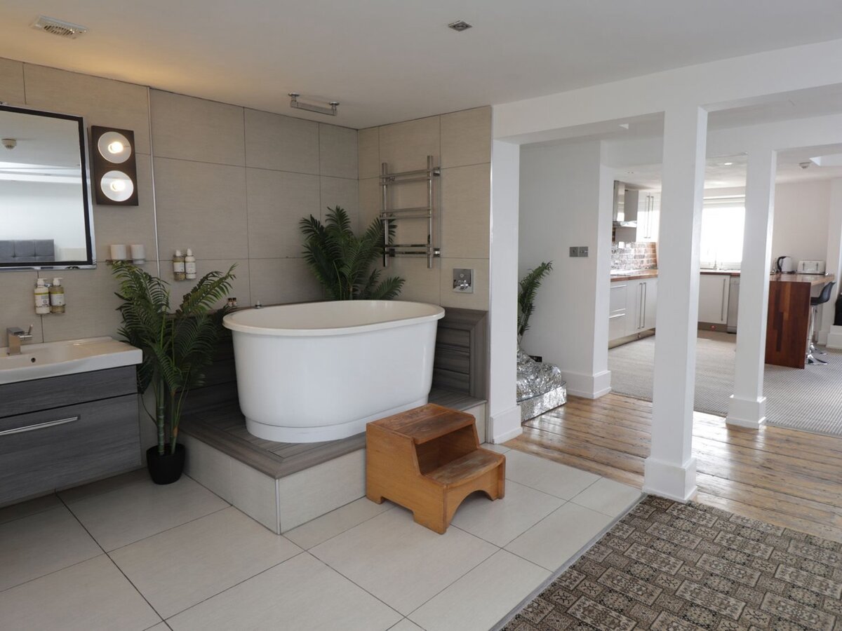 Manhattan Suite — freestanding bath on raised platform open to the bedroom