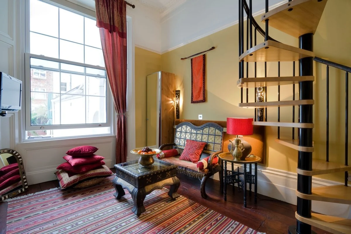Zanzibar House bedroom sitting room with spiral staircase, Indian bench and jewel-coloured cushions