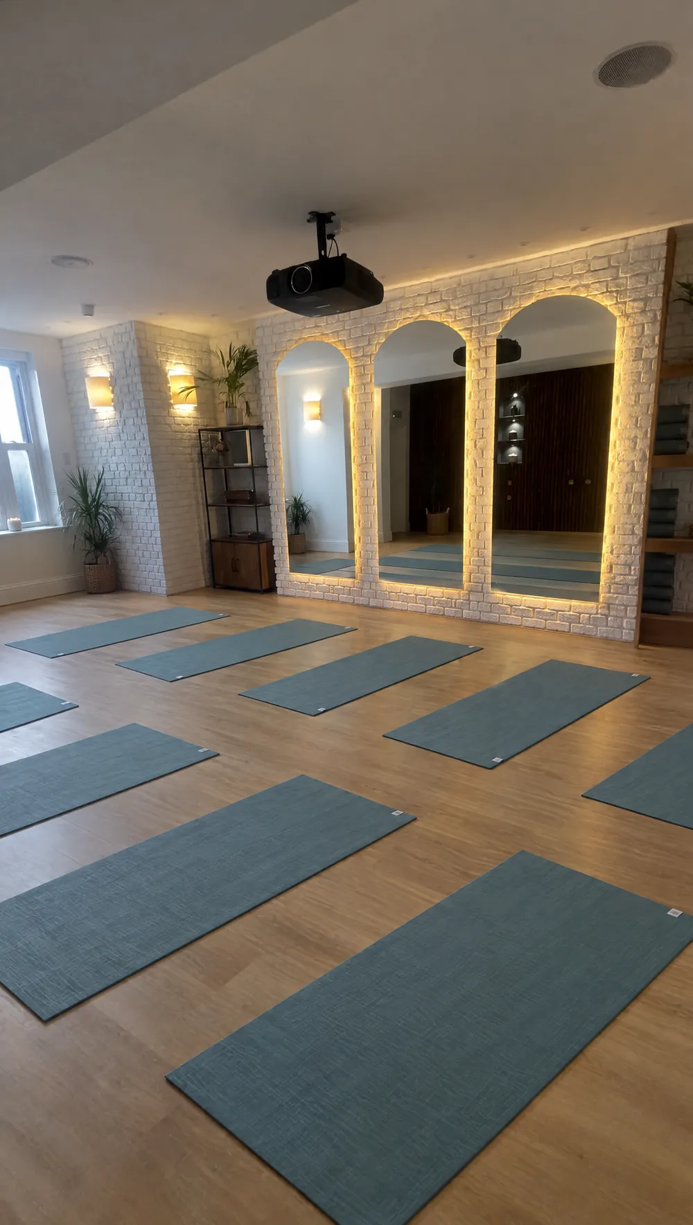 Private yoga and wellness studio at Zanzibar House, St Leonards-on-Sea — yoga mats laid out before three softly lit arched mirrors
